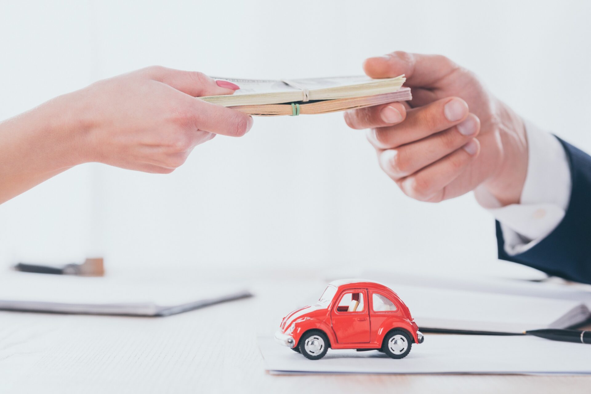 Person taking money from woman near red toy car Person taking money from woman near red toy car